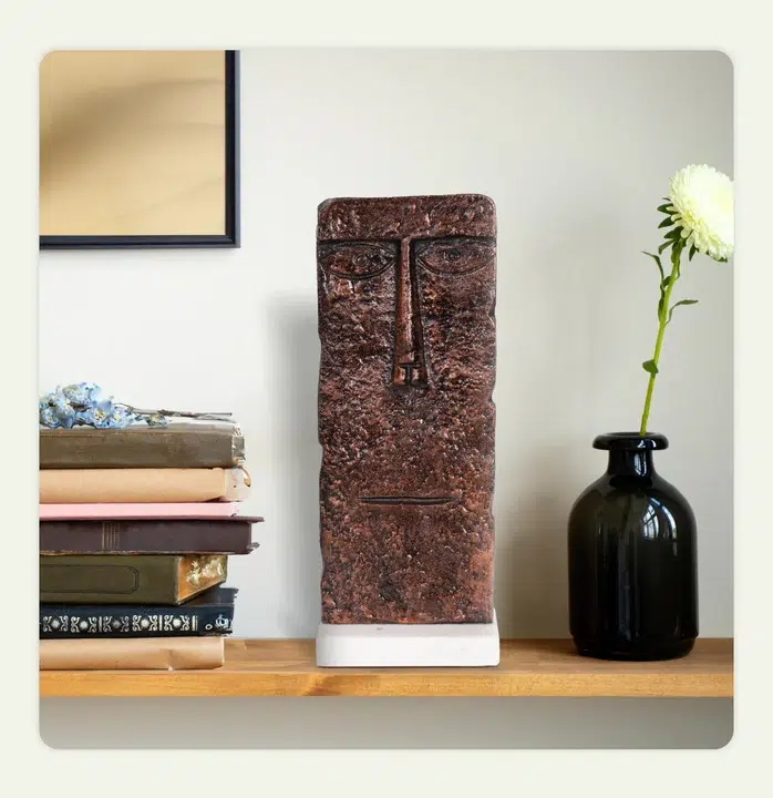 A modern sculpture placed along with a vase and a stack of books